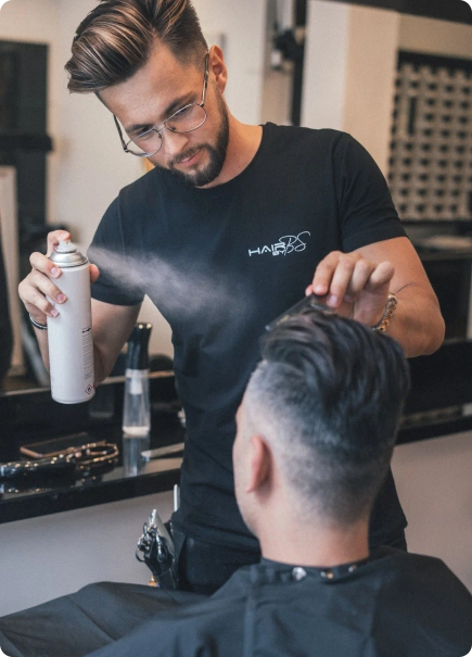 A barber using a hair spray on a client’s hair