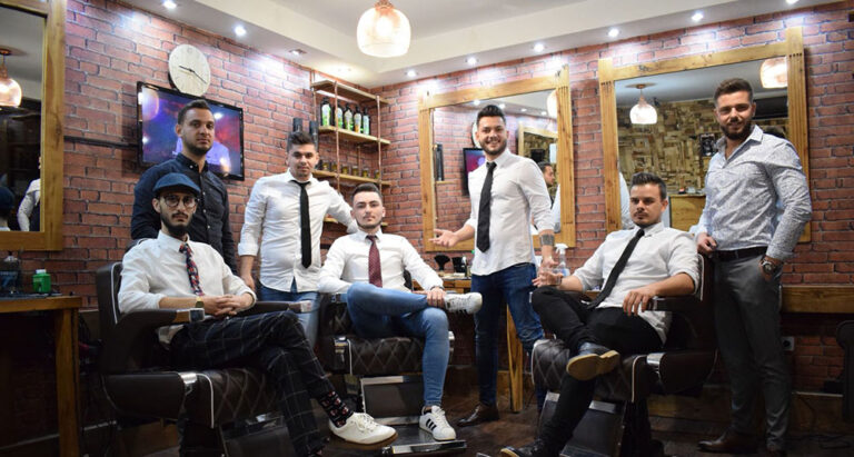 barbers sitting in a barbershop, posing for a photo