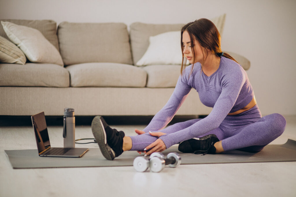 Woman watching an online fitness class and training from home 